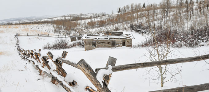 a snowy scene with fence and low cabin